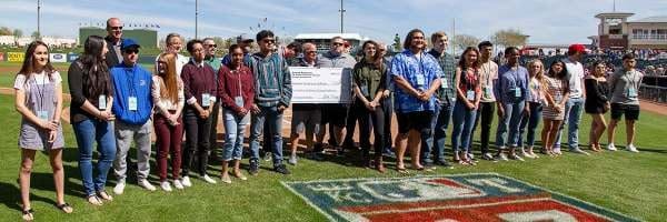 A group of people standing around each other holding a large check.