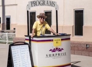 A man standing behind a cart with programs on it.