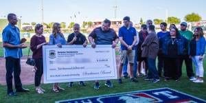 A group of people standing around holding up large checks.