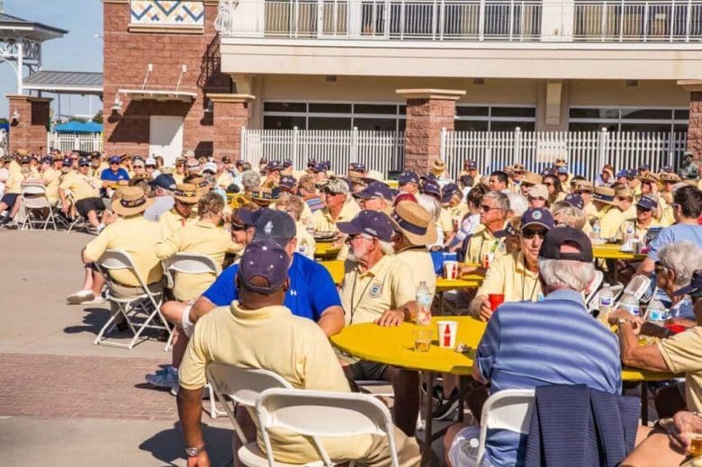 A group of people sitting at tables outside.