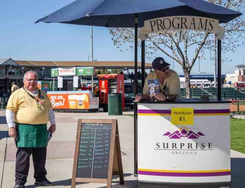 A man standing next to an outdoor vendor.