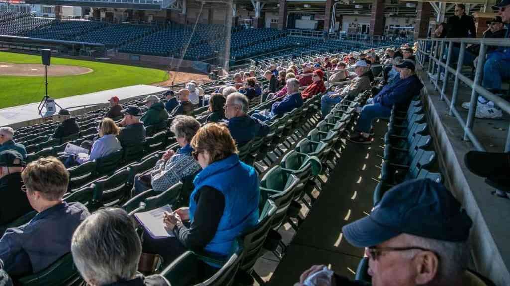 A group of people sitting in the stands at a baseball game.