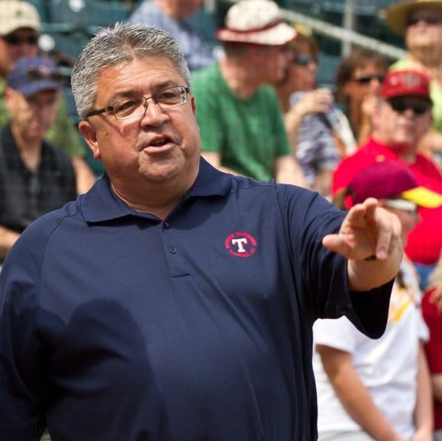 A man in blue shirt holding something up to the crowd.