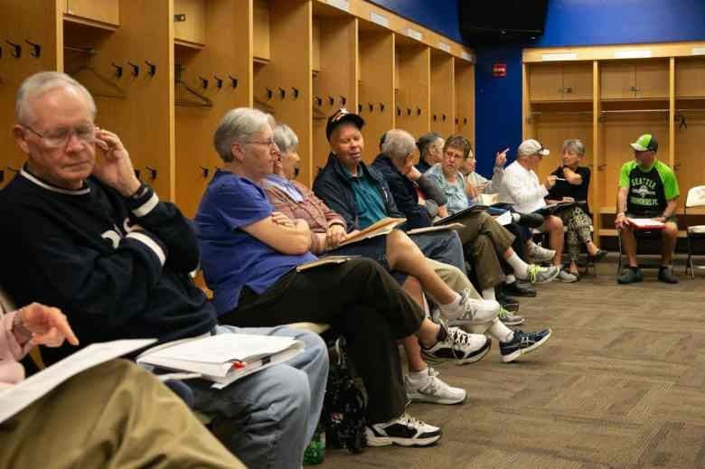 A group of people sitting in front of lockers.