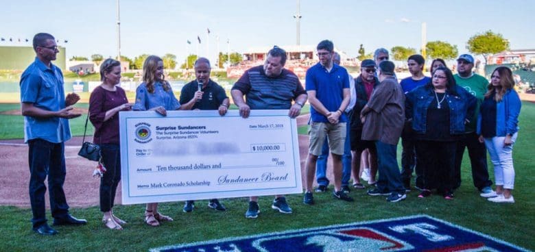 A group of people standing around holding up large check.