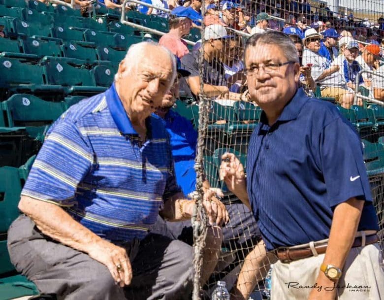 Two men sitting next to each other at a baseball game.